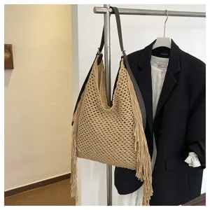 Gros plan sur le détail du sac hobo beige tricoté à la main, avec de superbes franges élégantes.