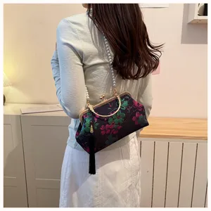 Detailaufnahme der chinesischen blumenbestickten Abendtasche mit Perlenkette und Quaste.