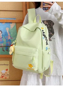 Light green nylon student backpack detail showing embroidered letters and front pocket design.