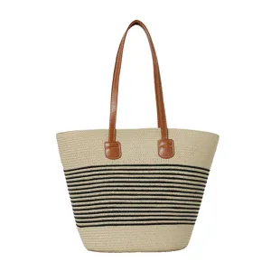 Detailed view of stylish straw woven striped tote bag with comfortable brown leather handles.