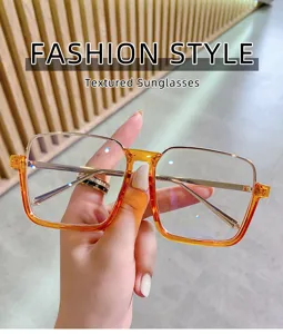 Vue détaillée de lunettes de soleil carrées tendance avec monture dégradée orange et branches.