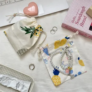 Vue détaillée d'un sac de rangement mignon en coton avec motif d'ananas et accessoires de bijoux.