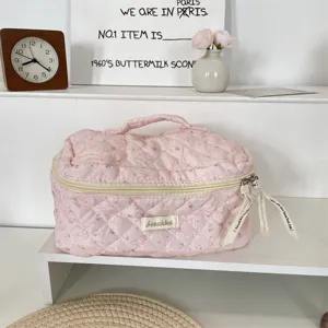 Pink quilted travel cosmetic bag with top handle, zipper closure, and cute pattern detail.