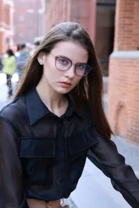 Close-up detail of stylish semi-metal frame anti-blue light glasses worn by model outdoors.