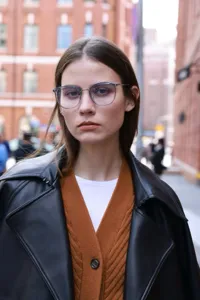 Close-up detail shot of stylish semi-metal frame eyeglasses worn outdoors by a model.