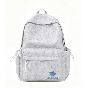 Grey nylon aesthetic backpack detail, featuring front zip pocket and blue flower embroidery.