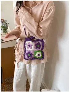 Vista dettagliata di una borsa a tracolla lavorata all'uncinetto con fiori viola e verdi.