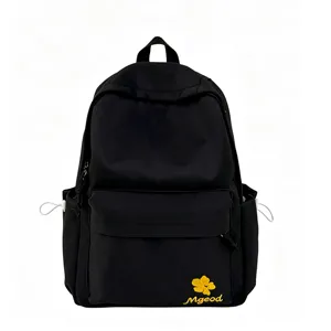 Detailed view of the black nylon backpack showing the front pocket and flower embroidery design.