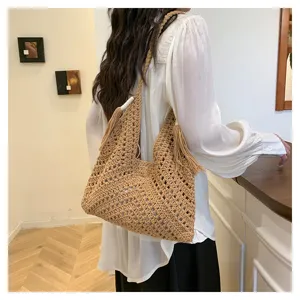Handmade woven hobo shoulder bag featuring intricate cut-out patterns and stylish tassels.