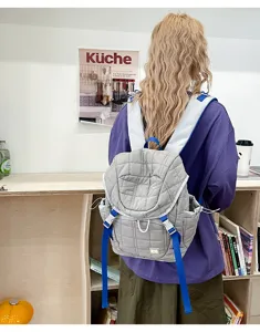 Vue détaillée d'un sac à dos matelassé gris doté de bretelles bleues et d'un rabat.