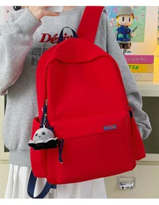 Detailed view of a vibrant red canvas backpack featuring a front pocket and cute octopus charm.