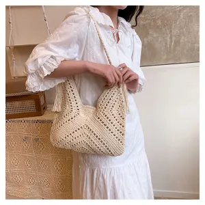 Detailed view of the vintage hollow crochet straw shoulder bag with delicate tassel accents.