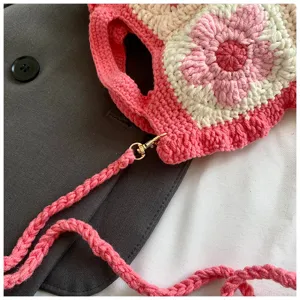 Vista dettagliata di una tracolla per borsa in crochet con fiori e trama artigianale.