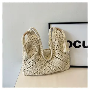 Detailed shot of a beige handmade hollow crochet tote bag with braided handles and tassels.
