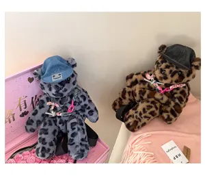 Nahaufnahme des süßen Leoparden Plüschbär Rucksacks mit Jeansmütze und verspielten Ketten.