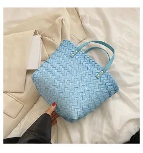 Light blue woven tote bag detail showing intricate braided texture and sturdy double handles.
