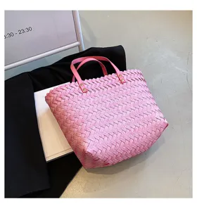 Detailed shot of a stylish pink woven tote bag with leather handles, lifestyle product view.