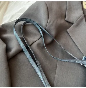 Λεπτομερης οψη ιμάντα τσάντας ώμου από vintage denim σε σκούρο φόντο σακακιού.