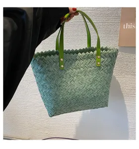 Green woven tote bag detail showing the basket-weave texture, leather handles and metal rivets.