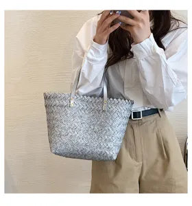 Detail view of a chic woven tote handbag featuring dual top handles and metallic rivet accents.