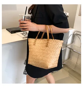 Detailed close-up view of a stylish woven straw tote bag featuring brown leather handles.