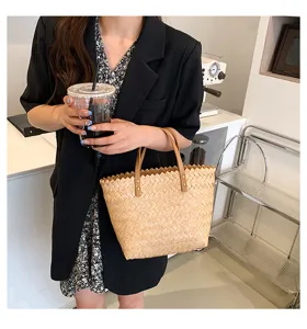 Detail view of a chic straw woven tote bag with brown leather handles and chic jagged rim.