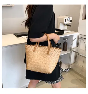 Detailed view of the stylish woven straw tote bag with brown leather handles and rivets.