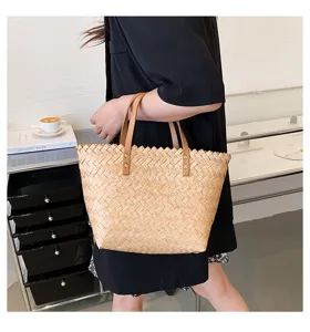 Detailed view of a fashionable straw woven tote bag with brown leather handles for women.