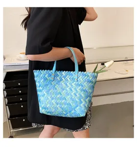 Detail view of stylish woven shoulder tote bag with blue gradient design and leather handles.