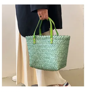 Close-up detail shot of the stylish green woven straw tote bag showcasing texture and handle.