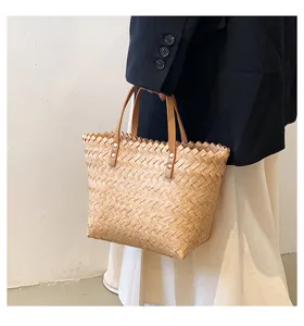 Detailed view of woven straw shoulder bag for women, featuring brown handles and chic design.