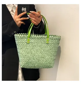 Green woven tote bag for women, stylish straw shoulder handbag with leather handles.