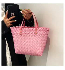 Pink woven tote bag detail, stylish shoulder shopping bag with pink handles and metal rivets.