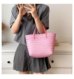 Detail view of pink woven women's shoulder bag featuring wave edge and chic handles.