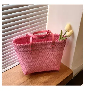 Pink woven tote bag detail showing delicate texture, leather handles, and metal rivet accents.