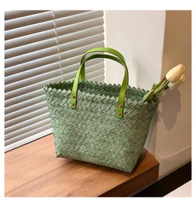 Green woven handbag detail showing textured straw material, leather handles, and metal rivets.