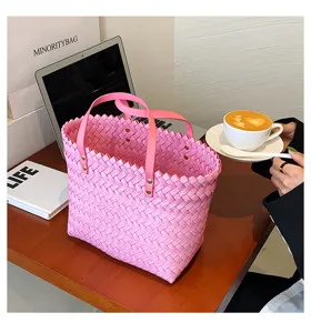 Pink woven tote bag detail showing intricate texture and sturdy pink leather handles.