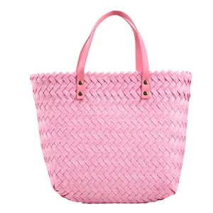 Pink woven straw tote bag for women, stylish shoulder handbag with leather handles and rivets.