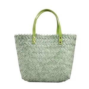 Close-up view of green woven straw tote bag for women with stylish light green handles.