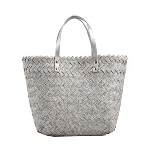 Detailed view of the grey woven tote bag featuring textured straw material and silver handles.
