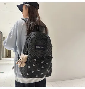 Detail view of a stylish star denim corduroy student backpack with cute bear pendant.