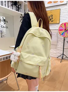 Vista detallada de la bonita mochila amarillo claro bordada con lazos y osito de peluche.