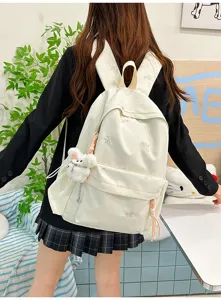 Mochila escolar de lona bonita para estudiantes con bordado de lazos y colgante de oso.