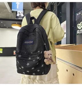 Black striped star denim backpack detail showcasing front pocket design and cute bear pendant accessory.