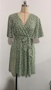 Green V-neck short sleeve wrap dress detail, white abstract print waist tie fabric texture.