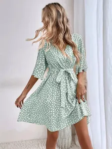 Detail view of a V-neck short sleeve polka dot dress, showing waist tie and fabric texture.