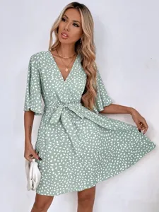Close-up detail of a V-neck short sleeve wrap dress with waist tie and spot print.