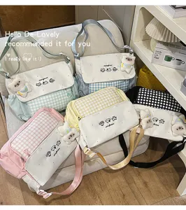 Detalle del bolso bandolera con tierno bordado de gato, patrón de cuadros y colgante de peluche.