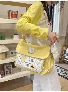 Cute yellow polka dot canvas messenger bag for school girls with cat design and cute pendant.