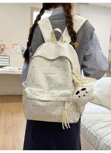 Vue détaillée d'un joli sac à dos blanc à motif d'étoiles avec pendentif en peluche.